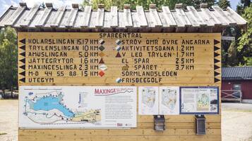 A wooden sign with directional information and distances to various locations.