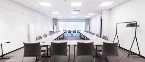 A conference room with a long table, four chairs, and a projector screen.
