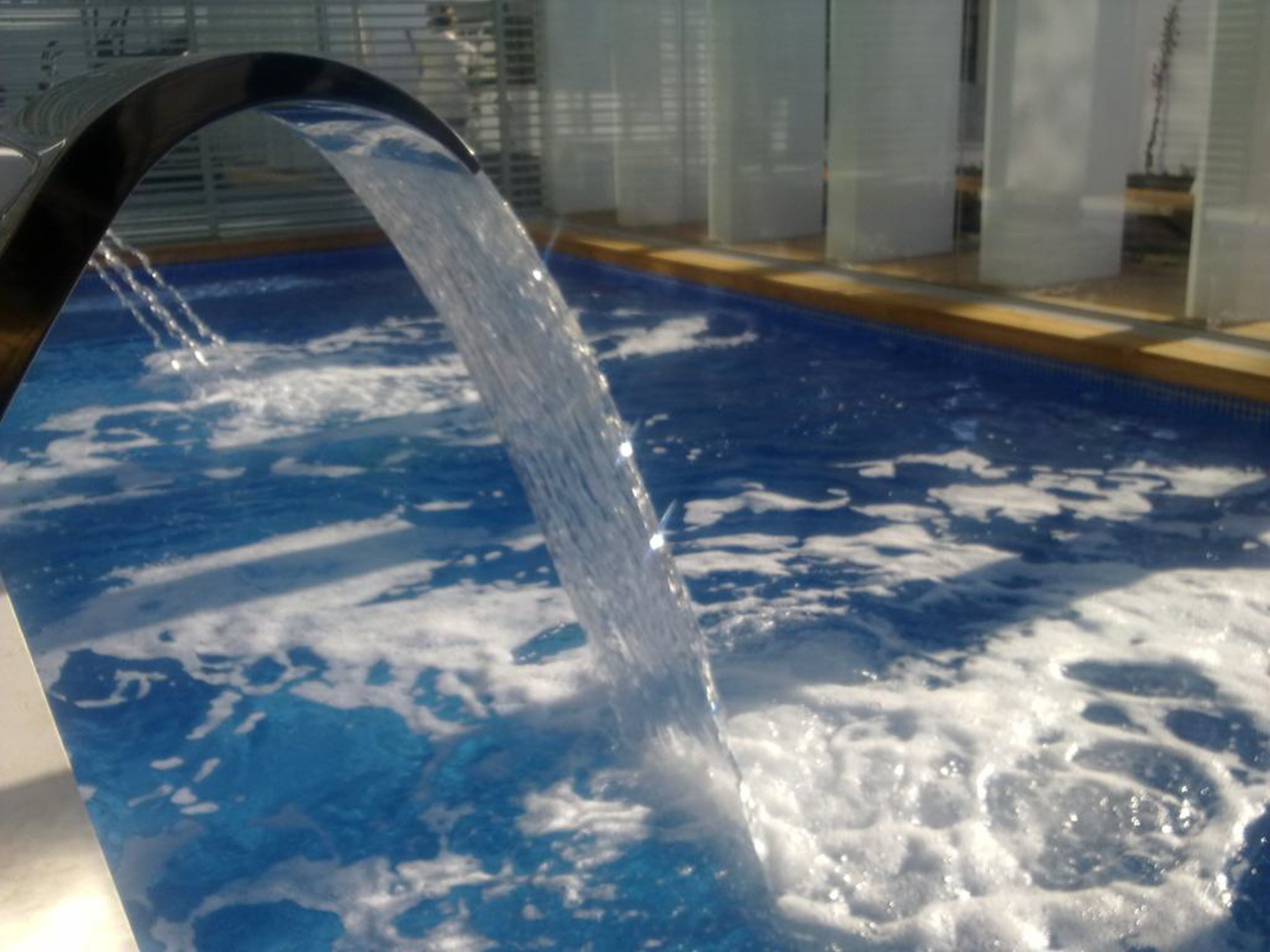Una piscina con agua cristalina y una fuente visible.