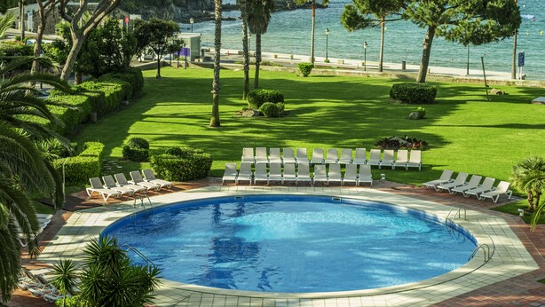 A pool area with lounge chairs and a view of the sea. - S'Agaró Hotel Spa & Wellness (Castell-Platja d'Aro)