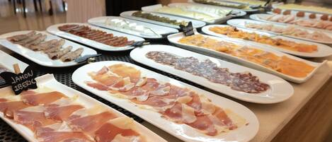 A buffet with various food items including meats and cheeses.