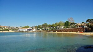 A coastal area with a clear blue sky, calm water, and a sandy beach. - S'Agaró Hotel Spa & Wellness (Castell-Platja d'Aro)