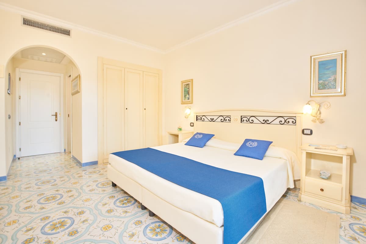 A bedroom with a bed, two nightstands, a door, and a hallway.