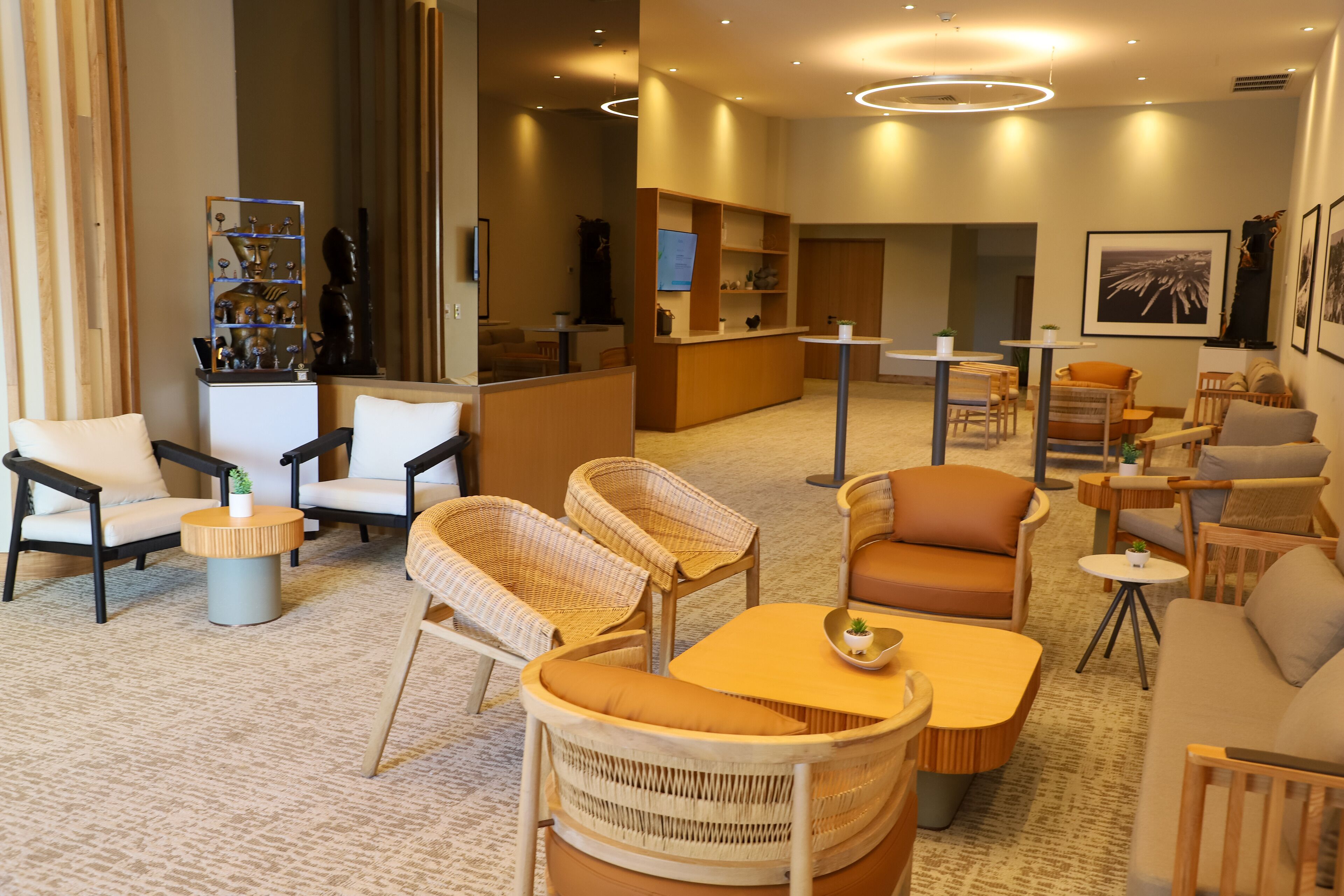 Un hall d’hôtel avec des meubles en osier, un comptoir de réception et un espace bar.