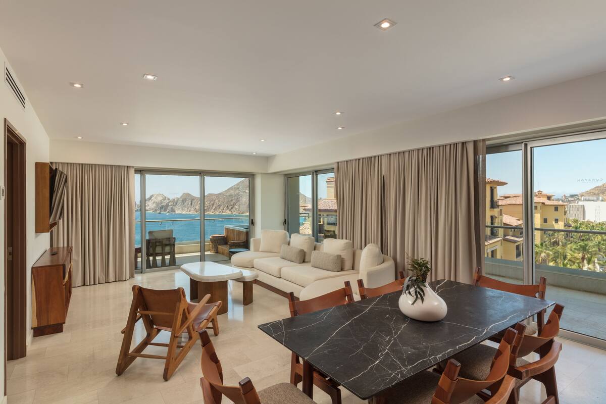 A spacious living area with a large dining table, comfortable seating, and a view of the sea.