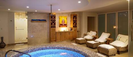 Uma área de spa com hidromassagem, cadeiras de vime e um armário de madeira com uma estátua de Buda.