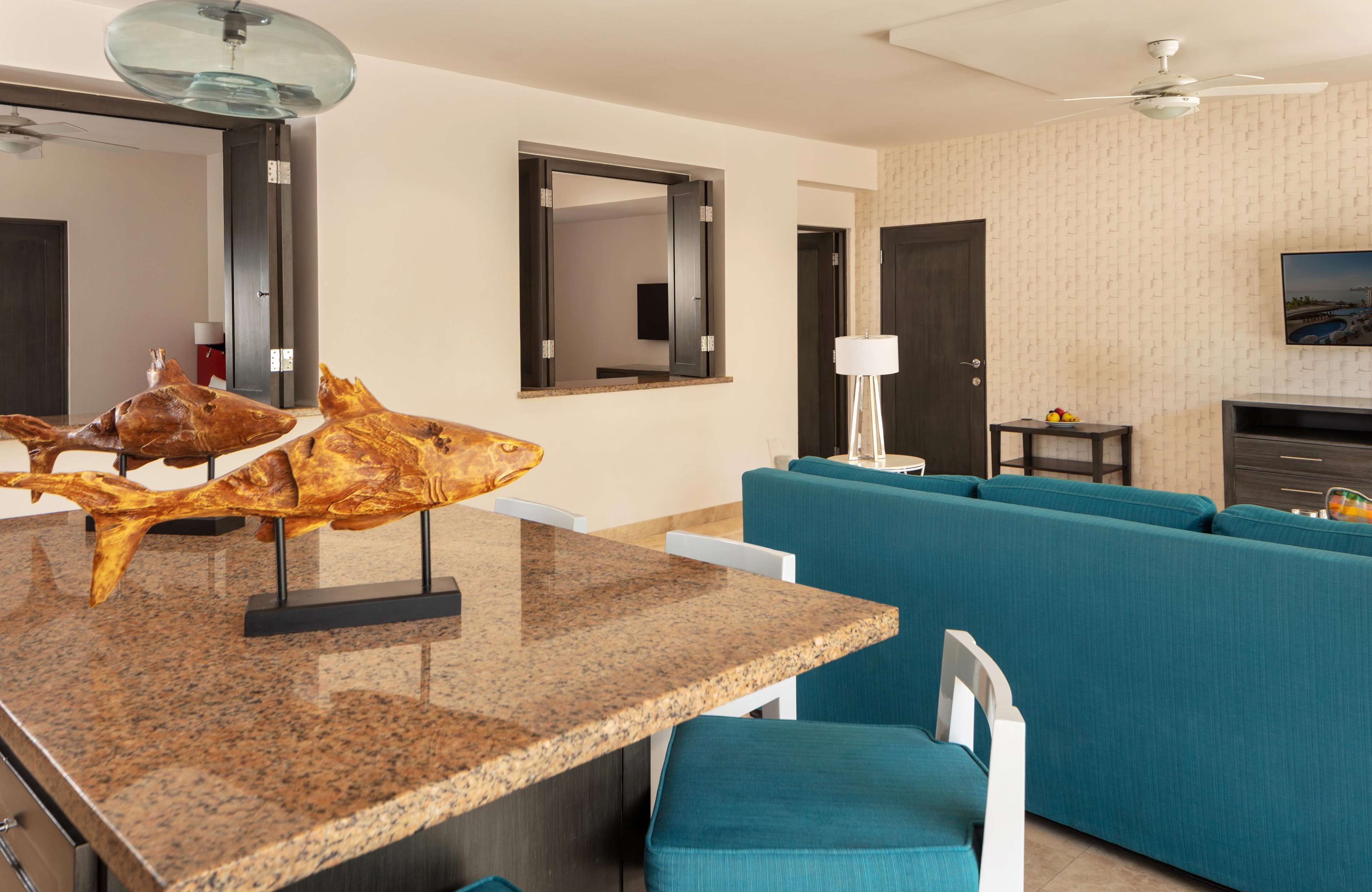 Un salon moderne avec un canapé bleu, une table à manger en granit et une grande sculpture de poisson.