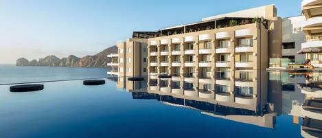 A modern hotel with a pool reflecting the building and surrounding landscape.