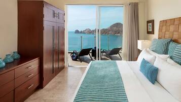 Een hotelkamer met een bed, een houten garderobe, een bureau met stoelen en uitzicht op zee.