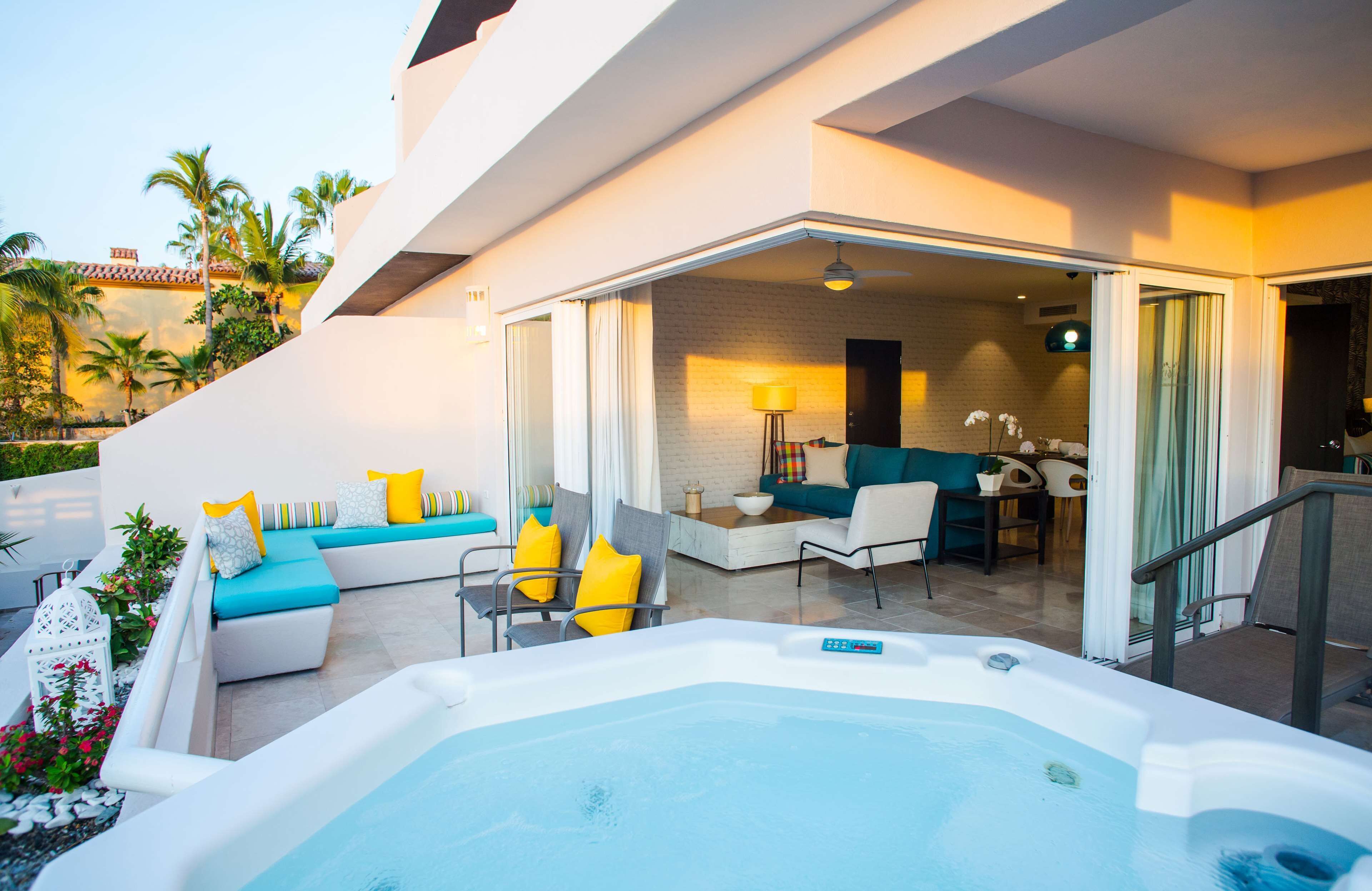 A modern outdoor living area with a hot tub, seating, and a view of the pool.