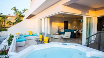 A modern outdoor living area with a hot tub, seating, and a view of the pool.