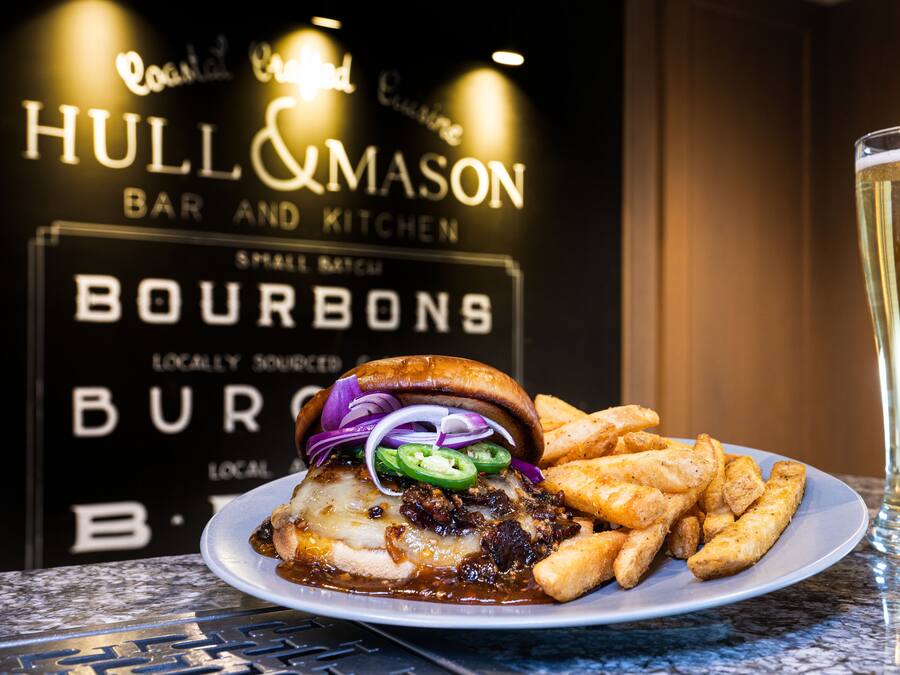 A plate of food with a burger and fries, a glass of beer, and a sign for 'Hull & Mason Bar and Kitchen'.