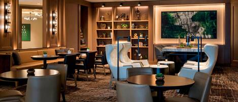 A modern hotel lobby with a seating area, a reception desk, and a large abstract painting.