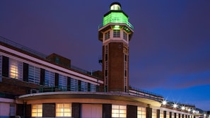 Een gebouw met een opvallende toren, voorzien van een klok en groene verlichting bovenop.