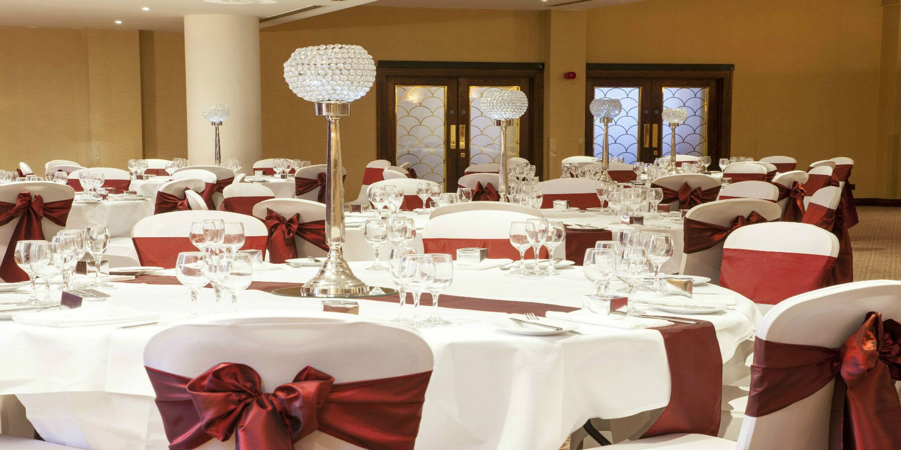 A banquet hall with round tables set for dining, each with a centerpiece and glassware.