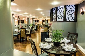 Un restaurante con varias mesas, sillas y una pared decorativa.