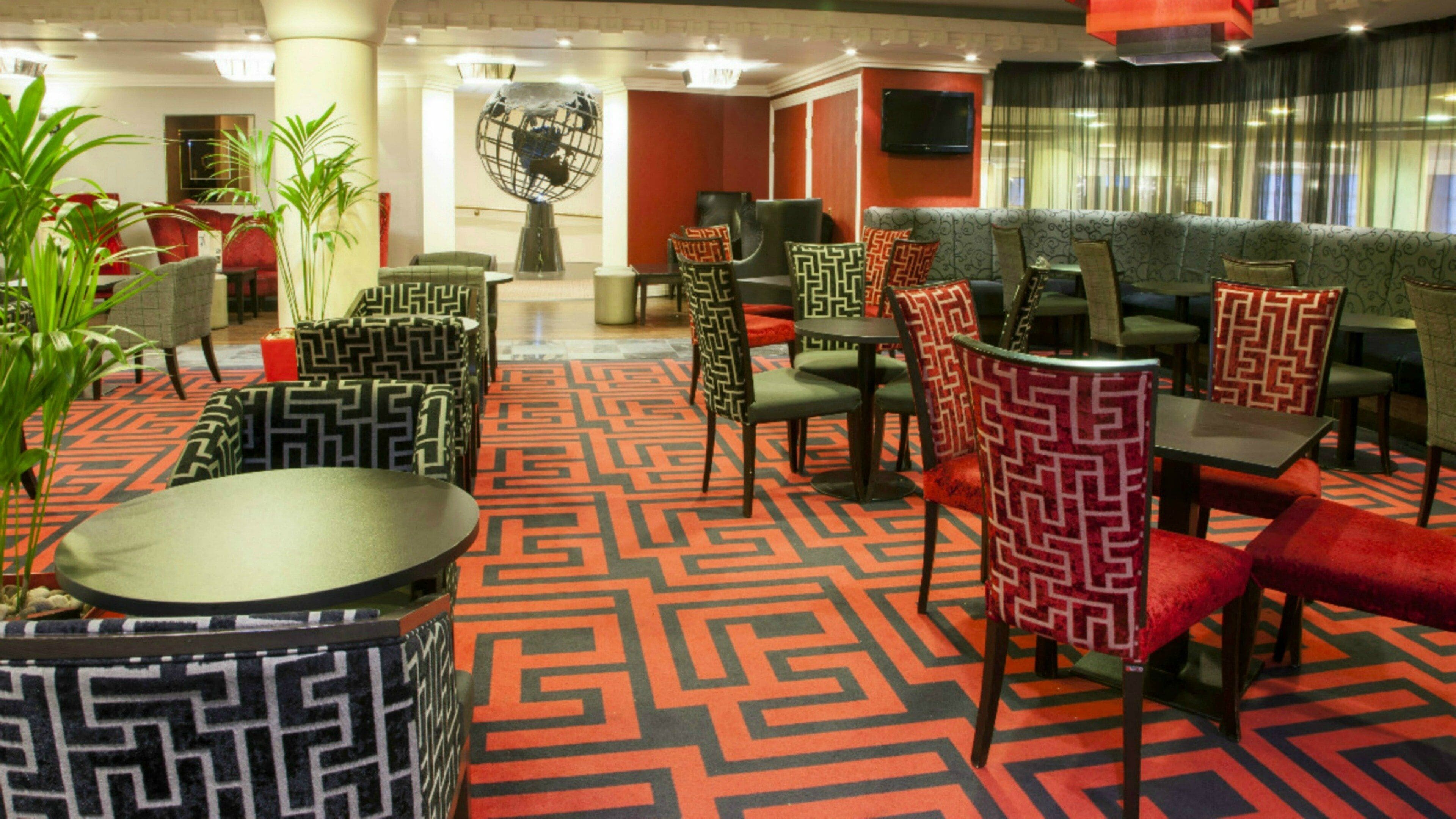 Un hall d’hôtel doté d’un tapis à motifs, d’espaces aménagés avec des sièges et d’une décoration en forme de globe terrestre.