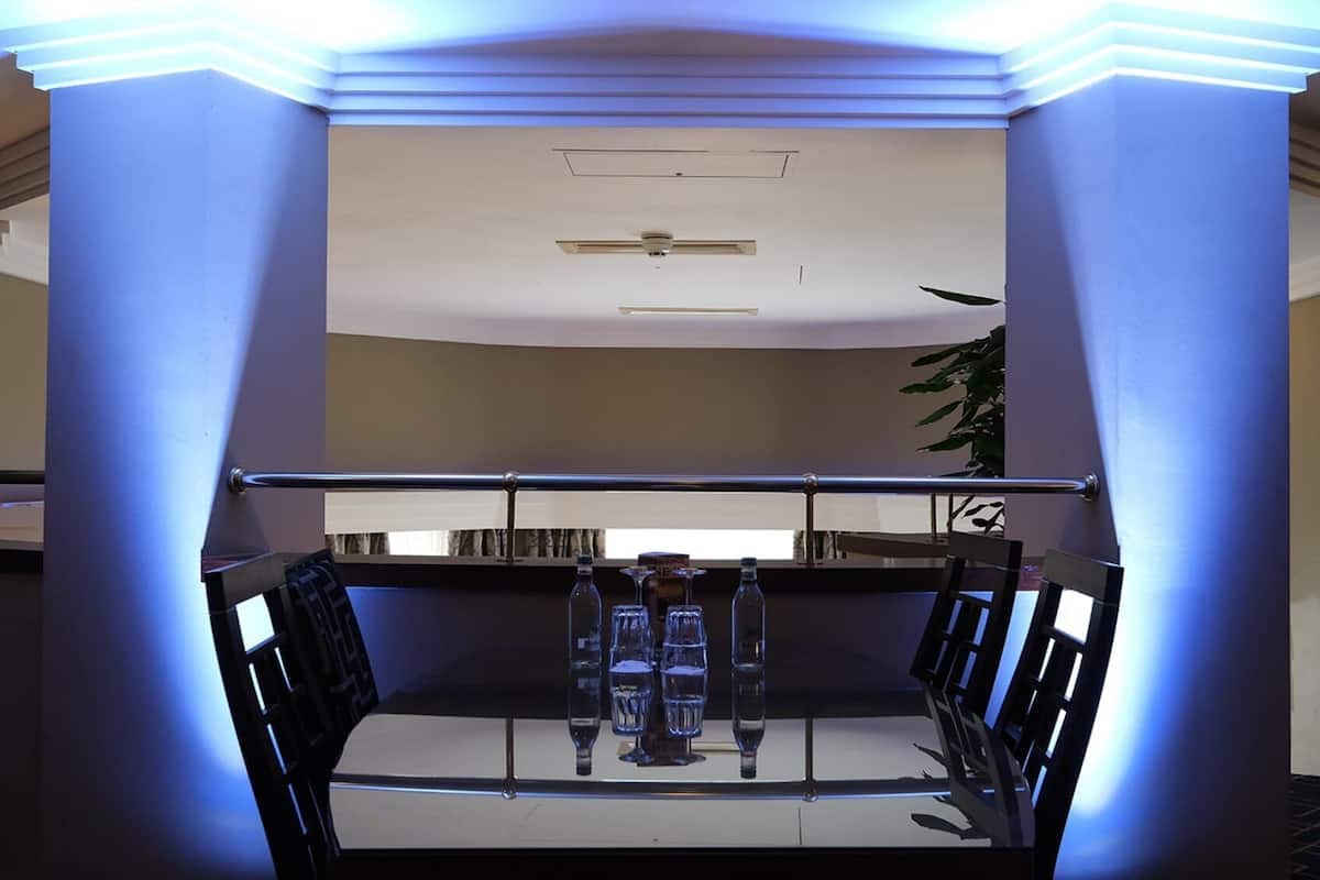 A room with a glass partition, a metal railing, and a ceiling fan.