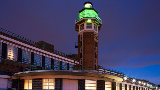 A building with a prominent tower featuring a clock and green lighting at the top.