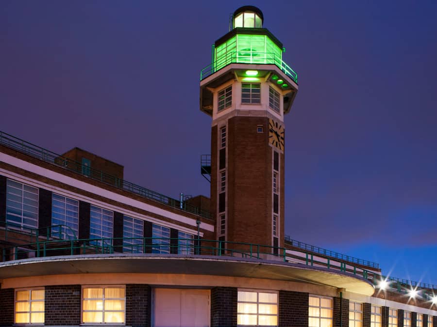 Un bâtiment doté d’une tour imposante, surmontée d’une horloge et d’un éclairage vert.