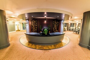 A reception area with a curved desk, seating, and decorative panels.