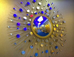 Espejo circular que refleja una habitación con alfombra azul y pared estampada.