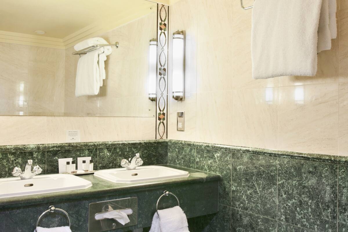 A bathroom with two sinks, a mirror, and a towel rack.
