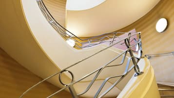 A spiral staircase with a metal railing and a yellow wall.