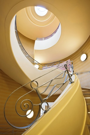 A spiral staircase with a metal railing and a yellow wall.