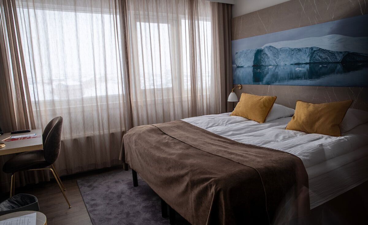 A hotel room with a bed, a desk, and a chair.