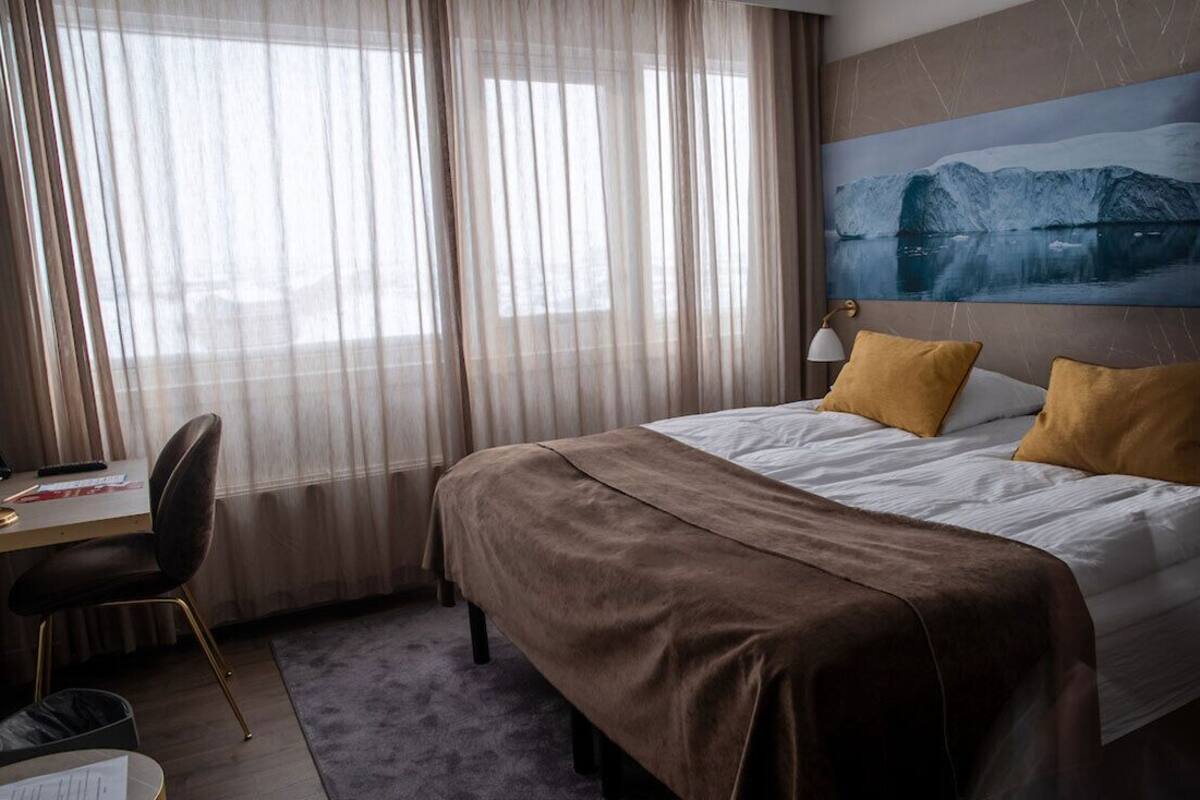 Una habitación de hotel con una cama, un escritorio y una silla.