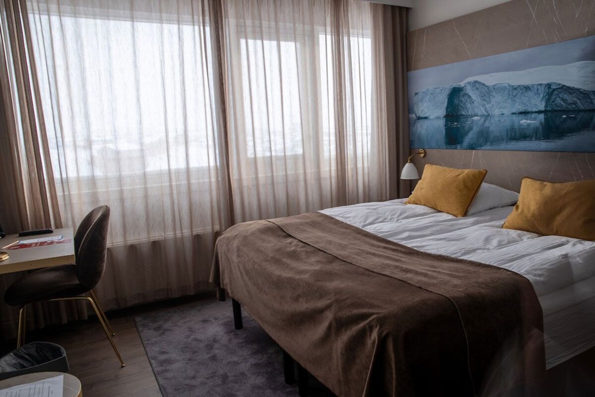 A hotel room with a bed, a desk, and a chair.