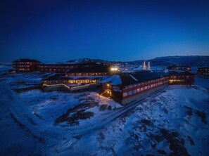 Un hotel con varias construcciones, incluyendo un edificio rojo destacado con el nombre "HOTEL RICHTIC" a la vista. Hay varias estructuras más pequeñas alrededor, y la zona está cubierta de nieve.