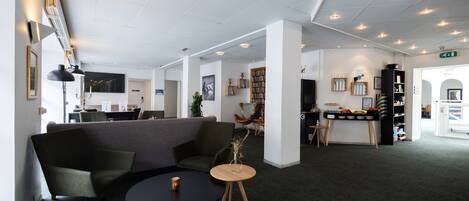 A modern lobby with a grey sofa, a round table, and a bookshelf.