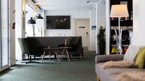 A modern lobby with a reception desk, seating area, and a bookshelf. - Milling Hotel Gestus (Aalborg)