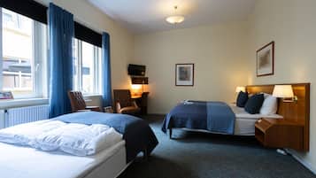 Une chambre d’hôtel avec deux lits, un bureau, une chaise, une télévision et un tableau encadré au mur.
