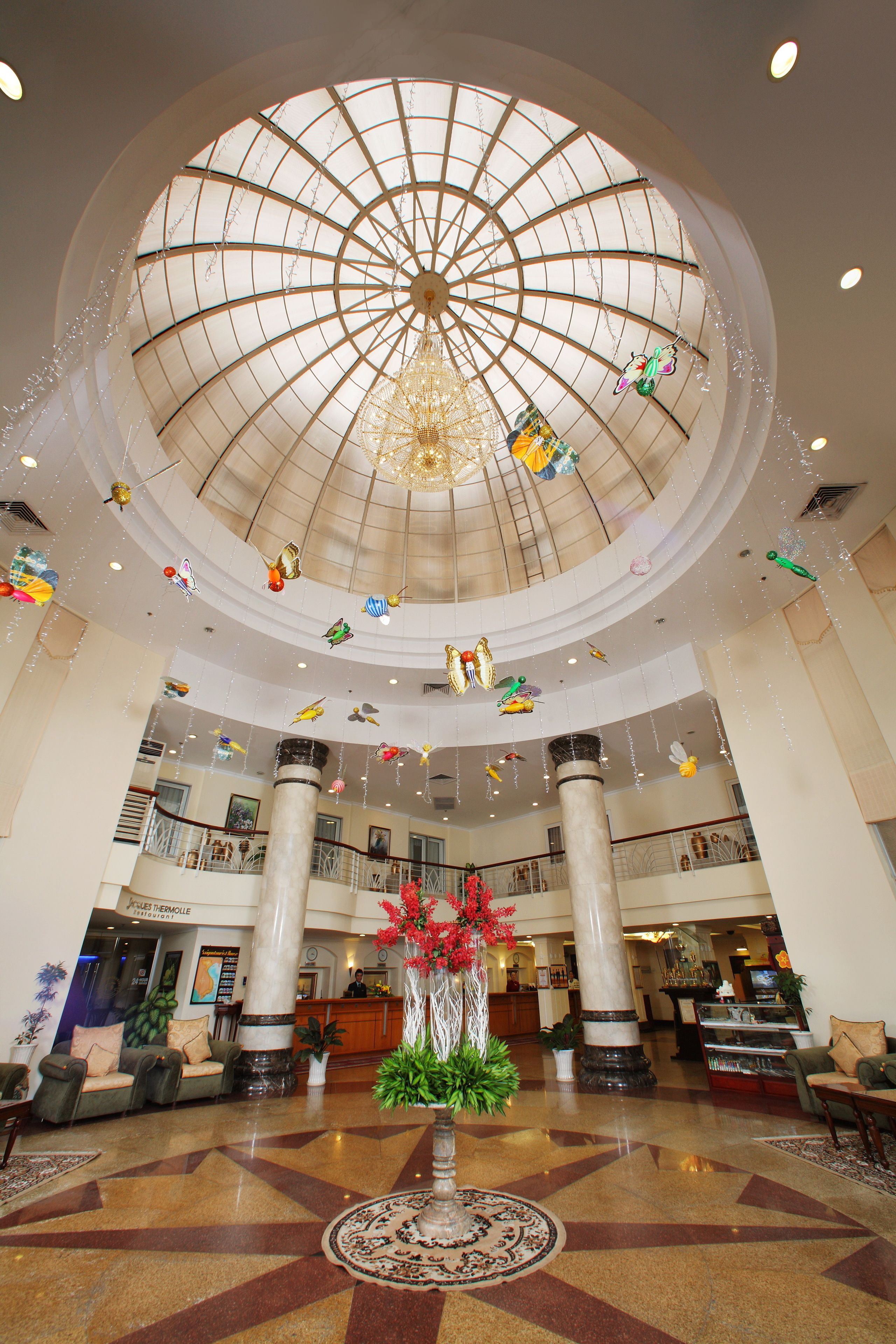 Eine geräumige Lobby mit hoher Decke, einem zentralen Kronleuchter und mehreren Ebenen.