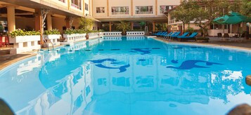 En swimmingpool med blå liggestole og et hvidt dækareal.