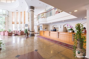 Welcome to our hotel lobby, featuring a spacious area with a reception desk, seating areas, and a mezzanine level.