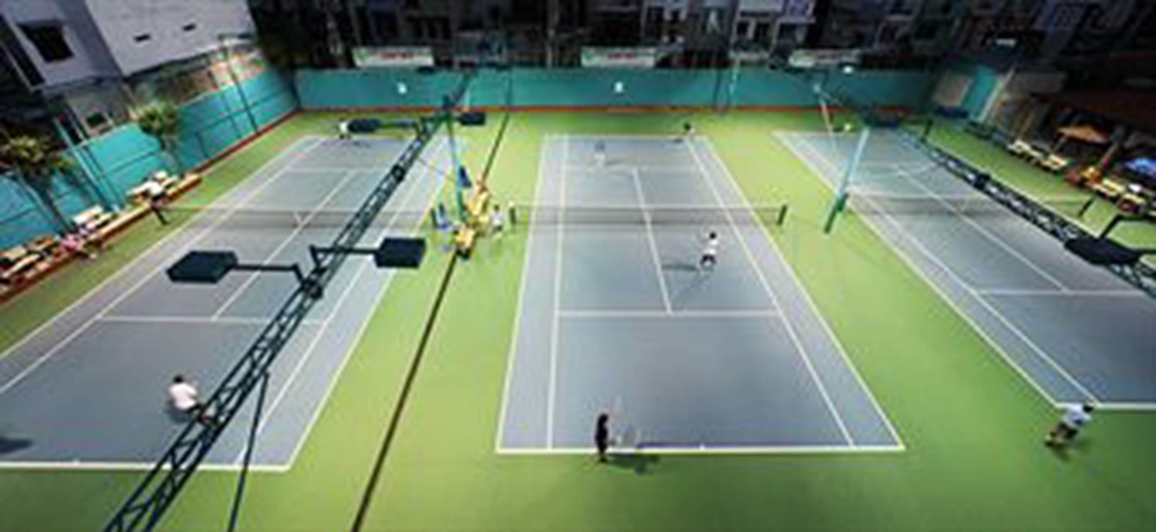 En indendørs tennisbane med flere baner, et net og et siddeområde.