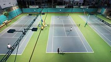 En indendørs tennisbane med flere baner, et net og et siddeområde.