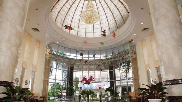 A spacious lobby with a high ceiling, large columns, and a central chandelier. - First Hotel (Ho Chi Minh City)