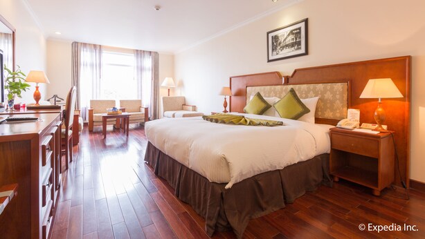 A hotel room with a large bed, bedside tables, a desk, and a chair. - First Hotel (Ho Chi Minh City)