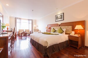 A hotel room with a large bed, bedside tables, a desk, and a chair.
