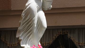 Una estatua de una mujer sosteniendo una cesta, ubicada frente a un edificio con un letrero que dice 'LIGONTOURIST'.