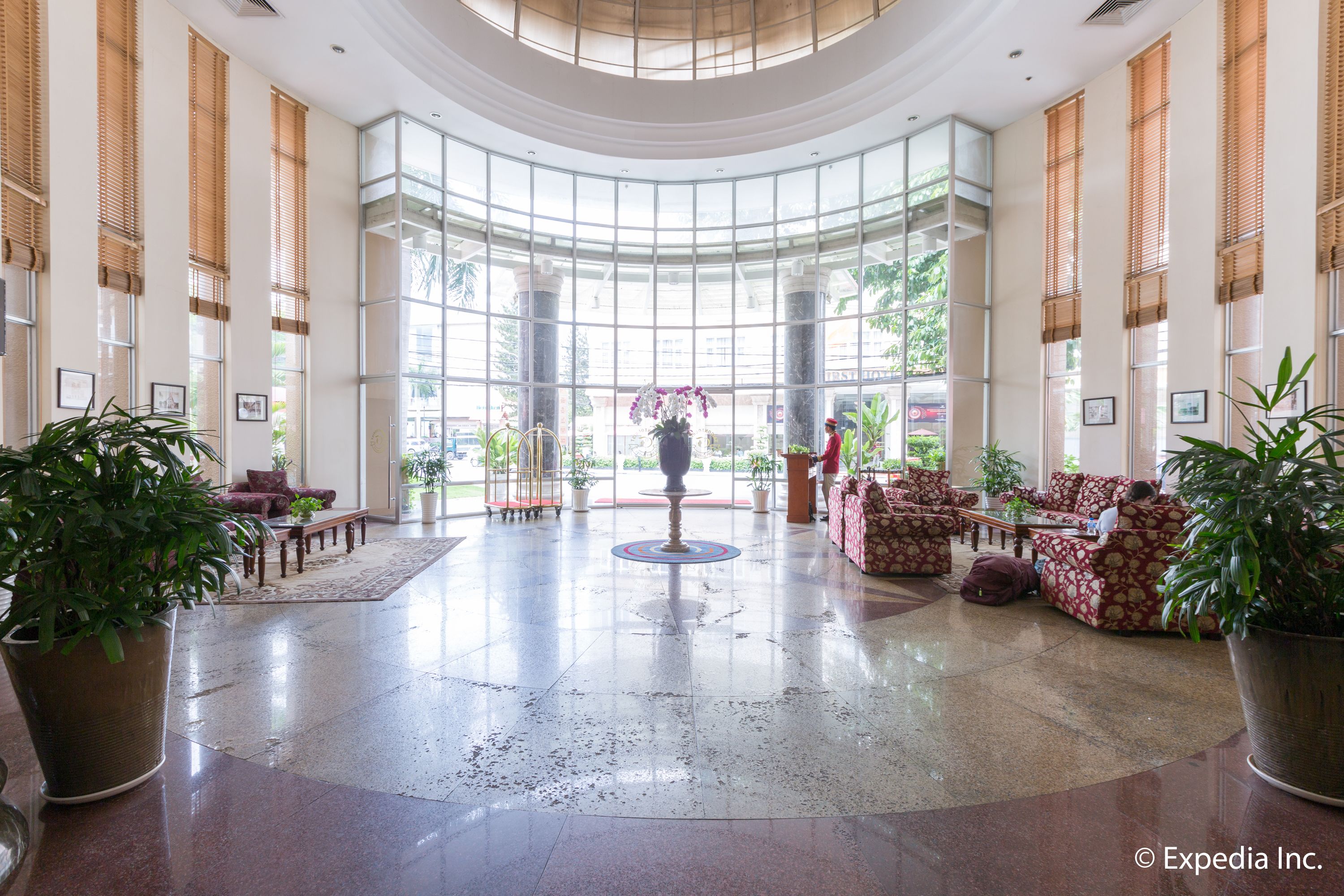 A spacious lobby with a high ceiling, large windows, and a central decorative fountain.
