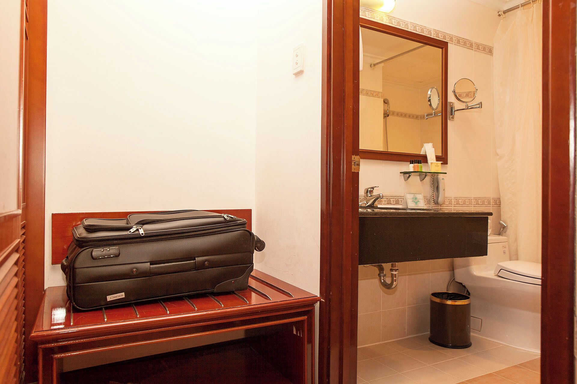 A bathroom with a wooden bench, a sink, a mirror, and a toilet.
