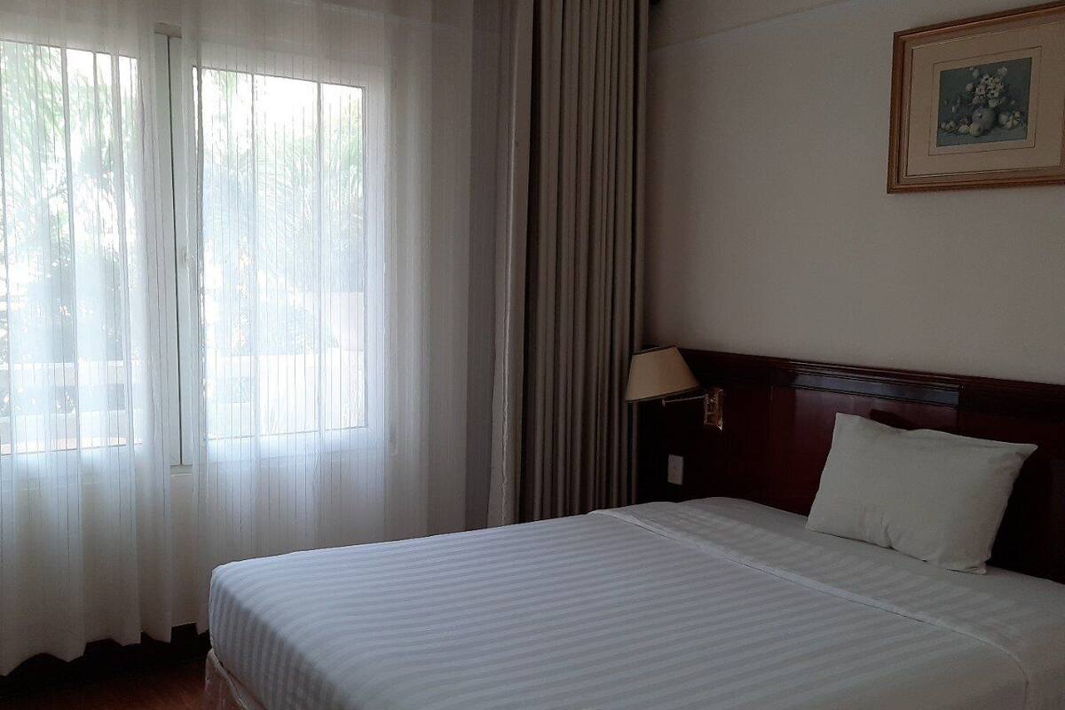 Una habitación de hotel con una cama grande, una mesita de noche, una lámpara y un cuadro en la pared.