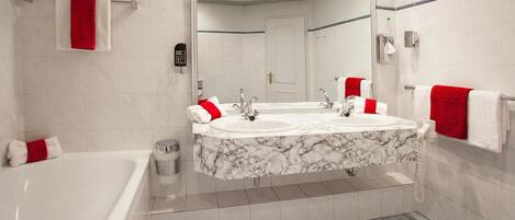 A modern bathroom with a large bathtub, two sinks, and a mirror above the sink.