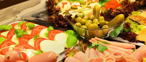 A buffet with various cold cuts, cheeses, and salads.